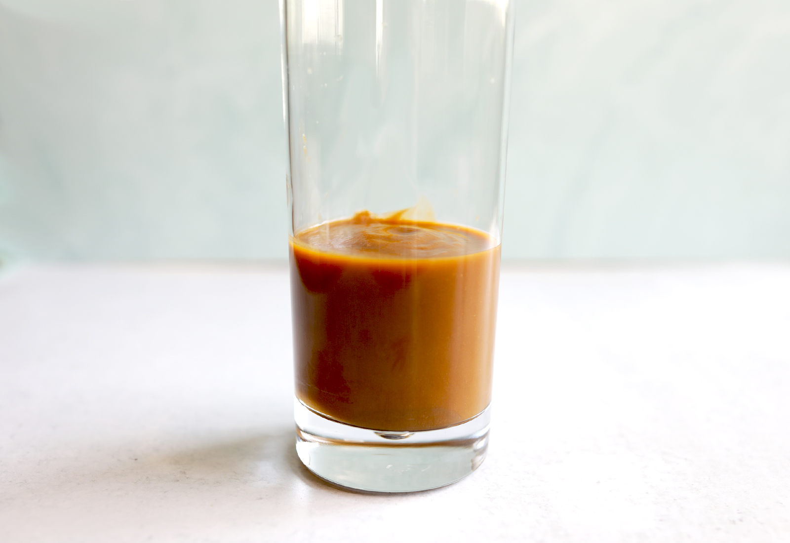 SaladPower’s light brown veggie purée is poured into a glass up close.